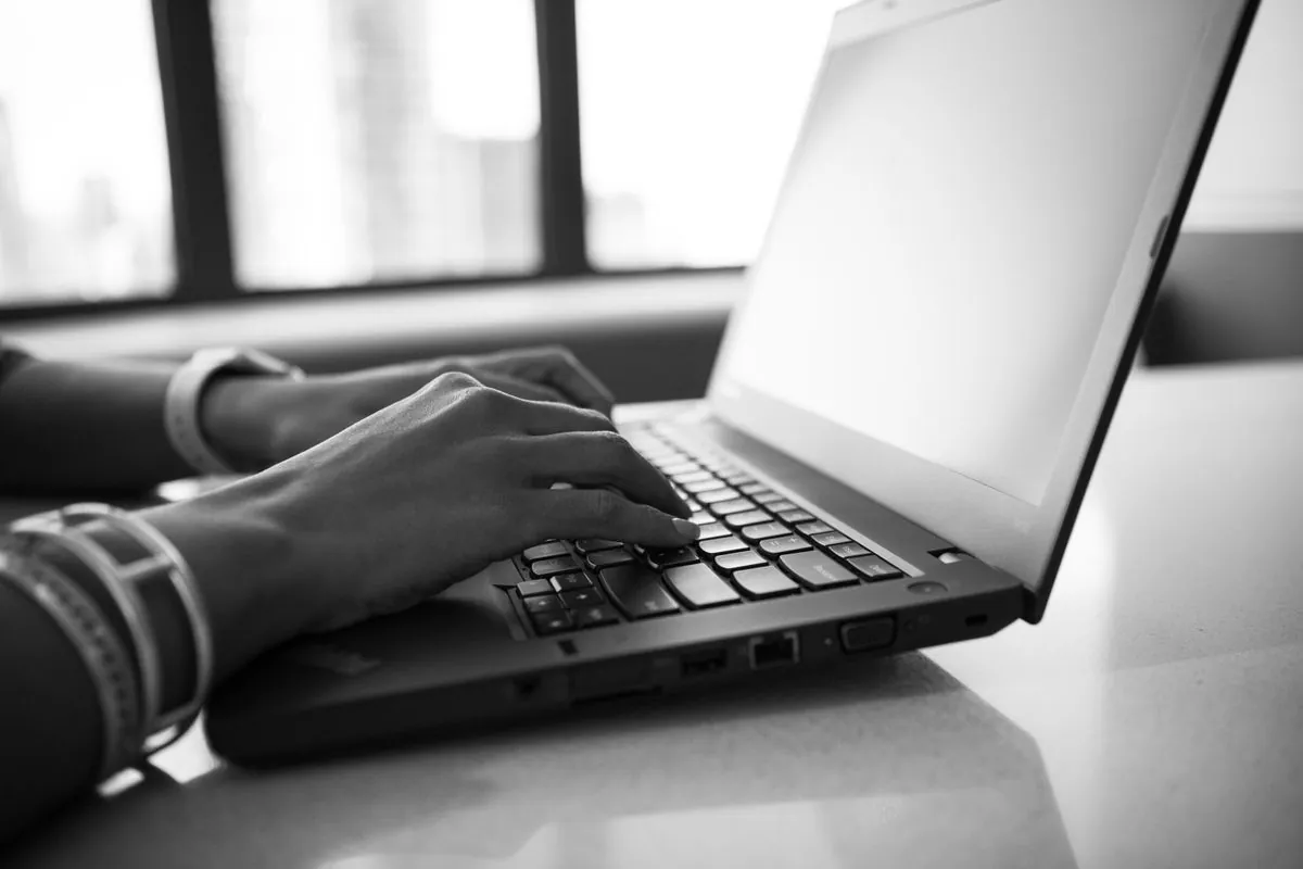 Close-up of hands typing on a laptop keyboard